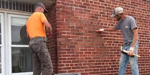 Two men working on brick wall maintenance.