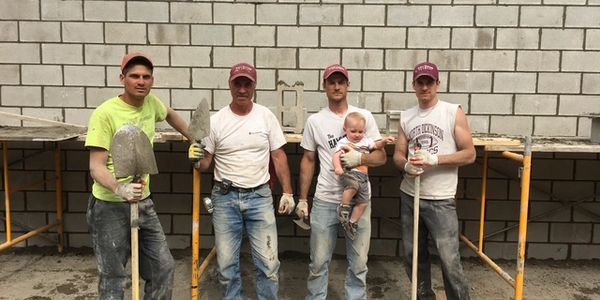 Four construction workers with a baby in front of a wall.