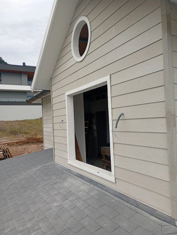 Parte externa de uma casa em construção com estrutura para janela.