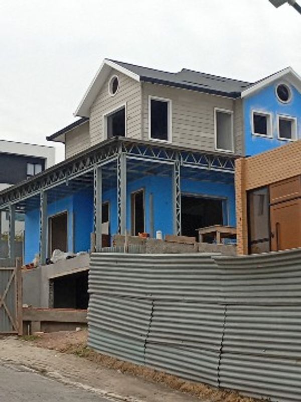 Casa em construção com paredes azuis e estrutura metálica.