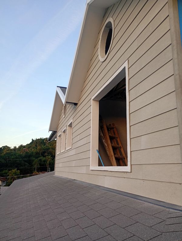Parede externa da casa com janelas sem vidro e uma escada dentro.