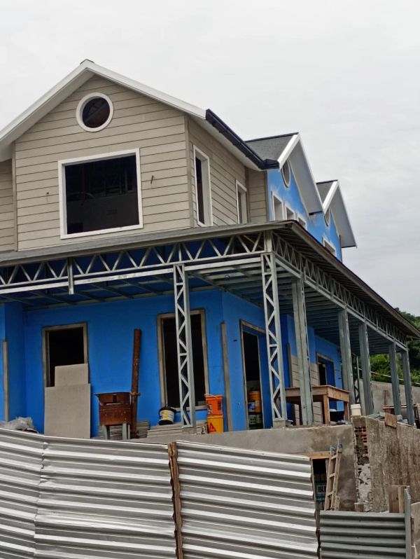 Casa em construção com estrutura metálica e parede azul.