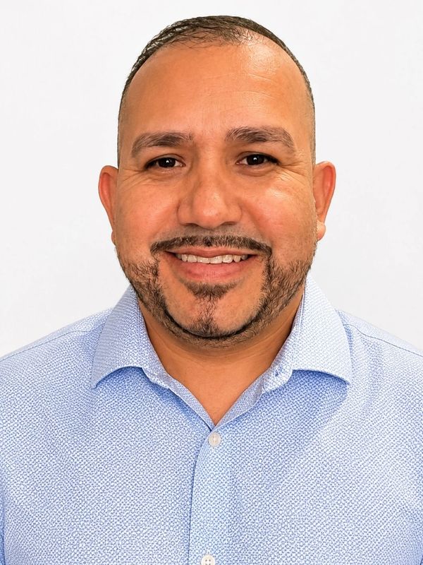 Smiling man in a light blue shirt against a white background.
