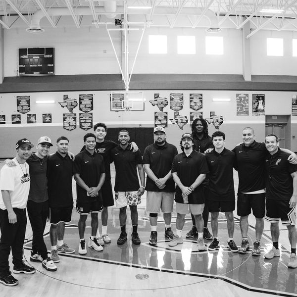 A basketball team posing together on a gym court.