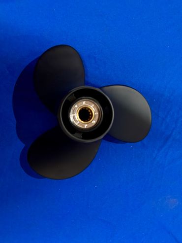 Black boat propeller on blue surface.