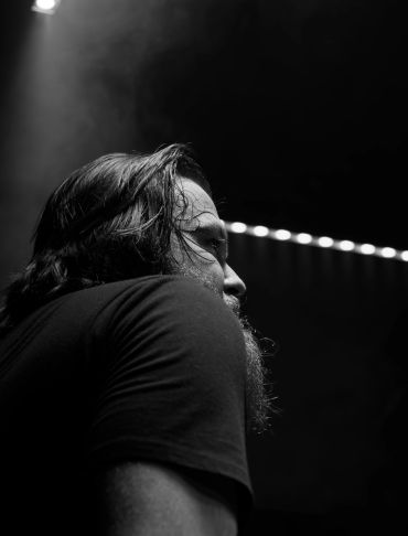 Black and white side profile of a man with long hair and beard.