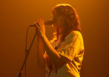 Singer performing on stage with warm lighting.