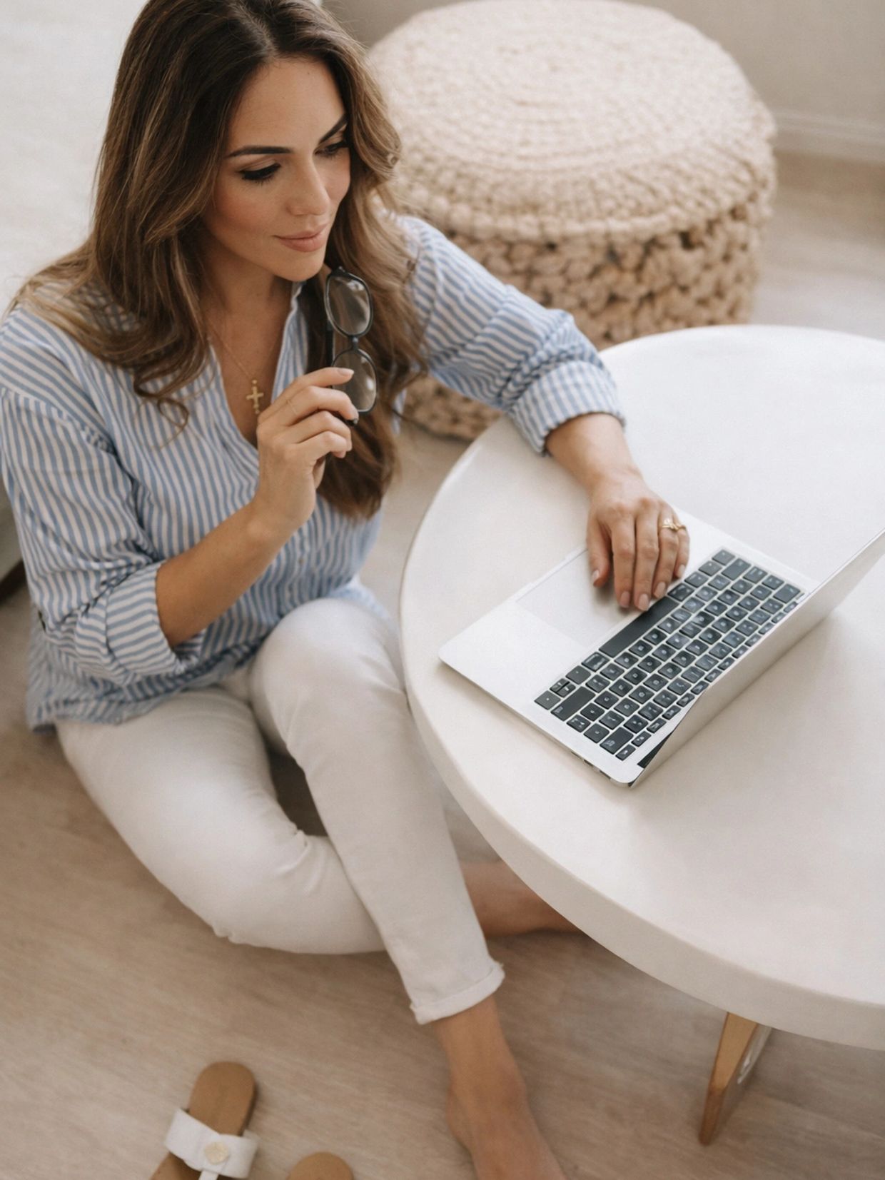Woman sitting on the floor working on a laptop at a round table.