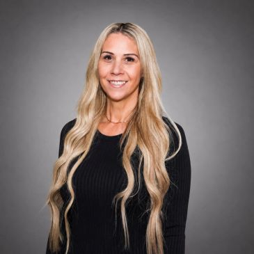 Smiling woman with long blonde hair in black top.