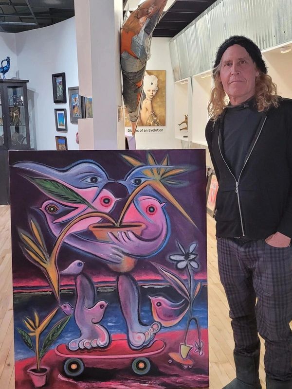 Man stands next to colorful surreal painting in art gallery.