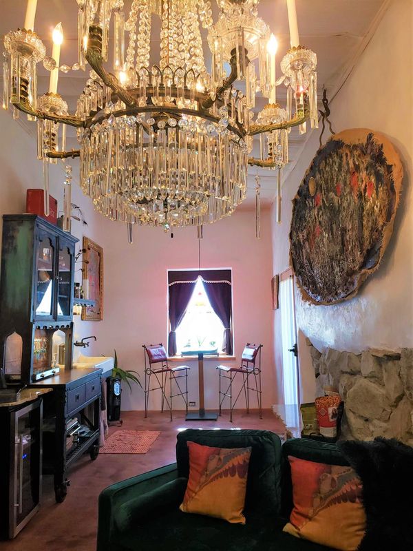 Elegant room with chandelier, vintage furniture, and cozy seating by a window.