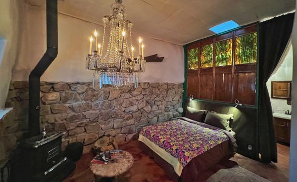 Cozy rustic bedroom with stone wall and crystal chandelier.