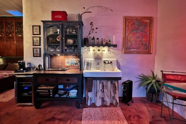 Cozy vintage kitchen corner with antique sink and cabinet under warm lighting.