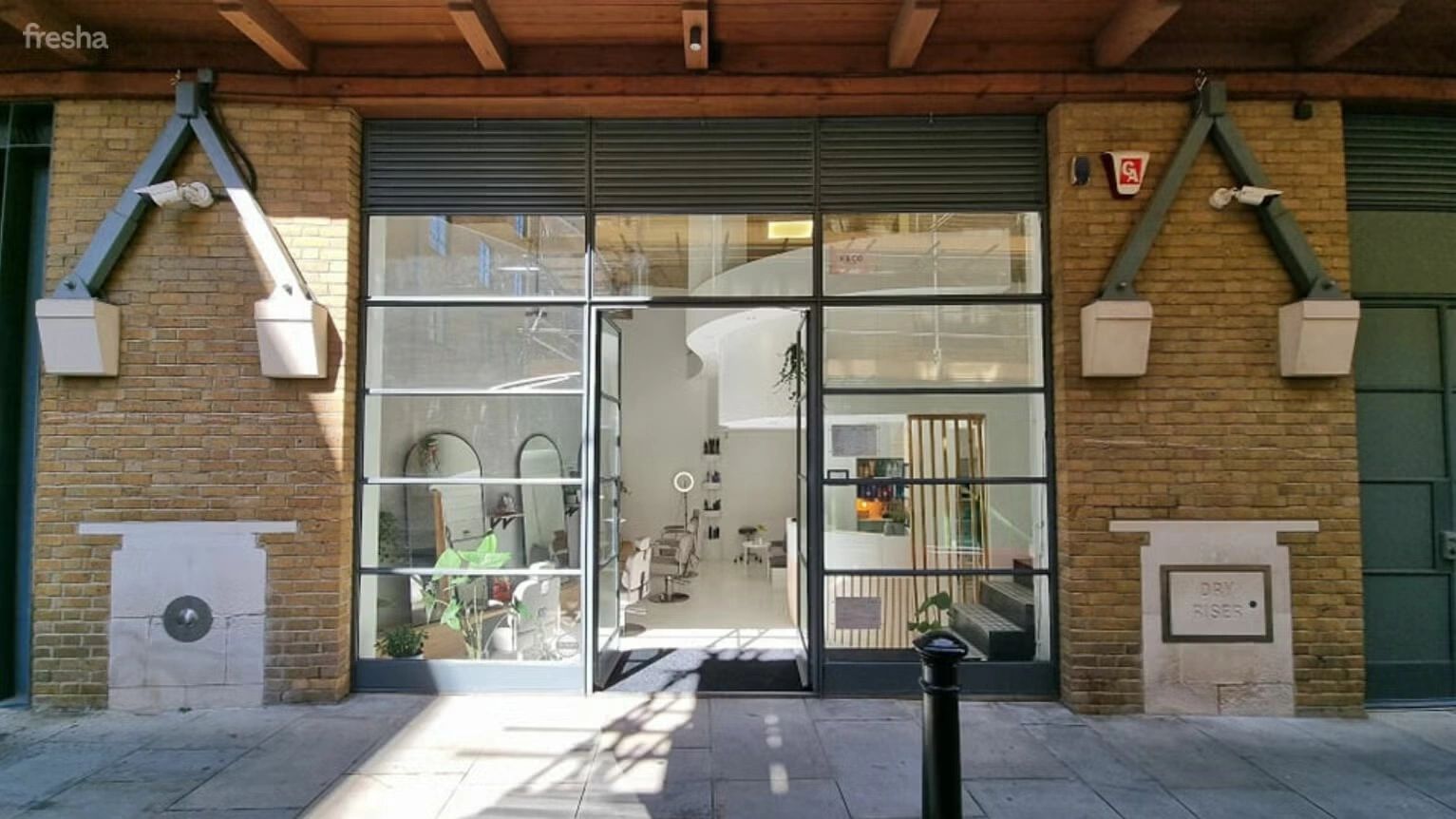 Modern salon entrance with large glass windows and brick walls.