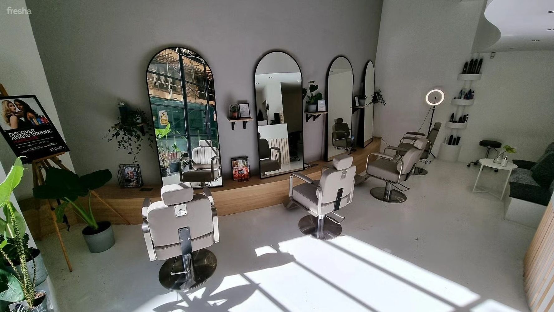 Modern hair salon with sleek chairs and large mirrors in natural light.