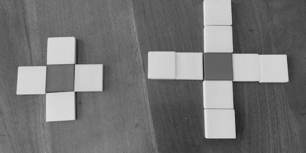 Two crosses made of yellow and blue square tiles on a wooden surface.