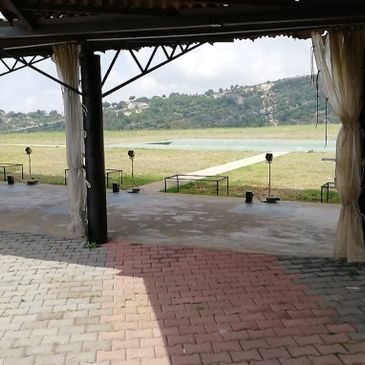 Covered patio overlooking a grassy field and hills in the distance.