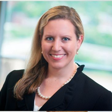 Maureen Johnson wearing a black jacket and pearl necklace.