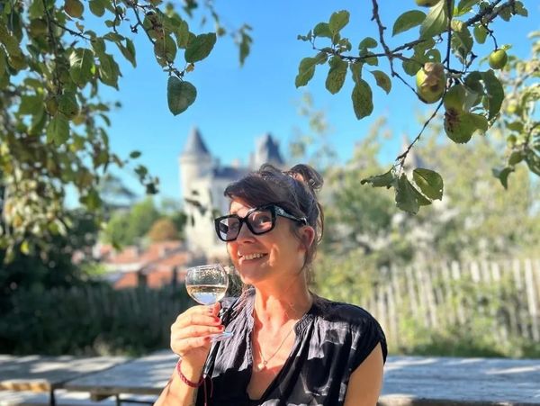 A woman enjoying a glass of wine outdoors on a sunny day.