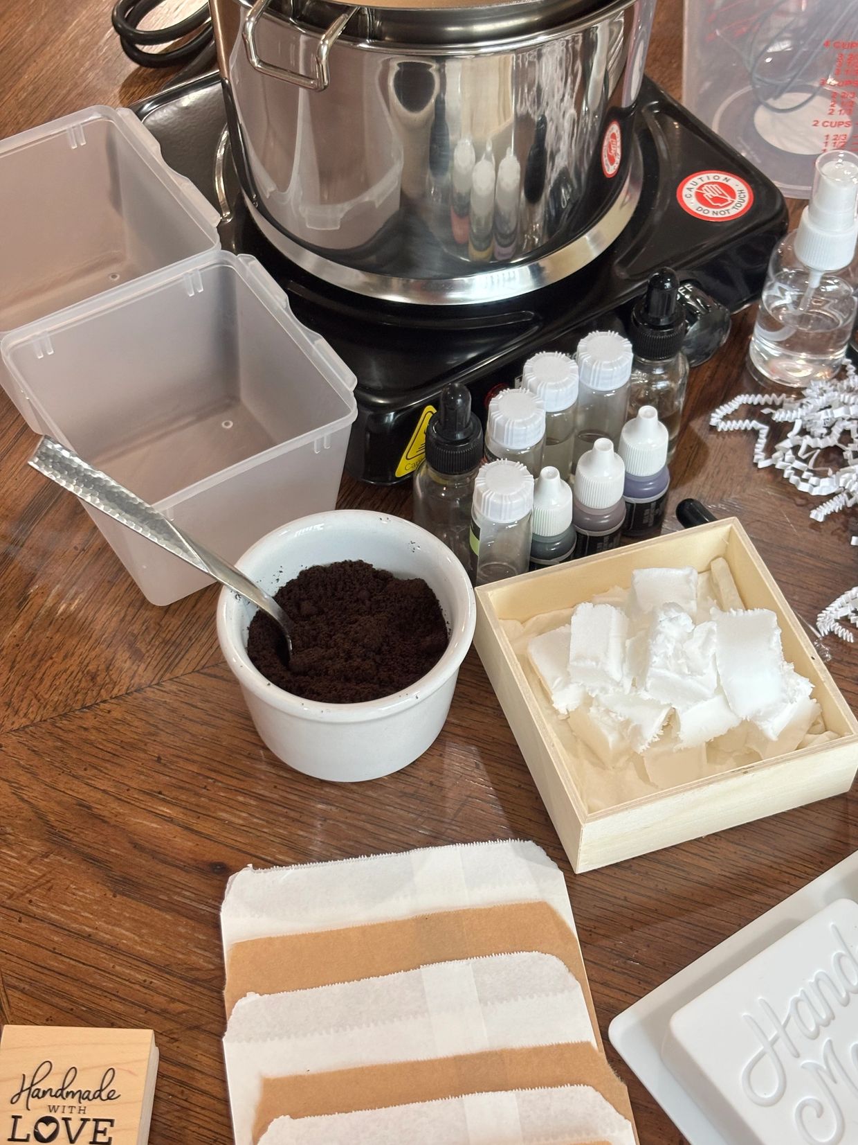 Soap-making supplies including molds, oils, and a double boiler.