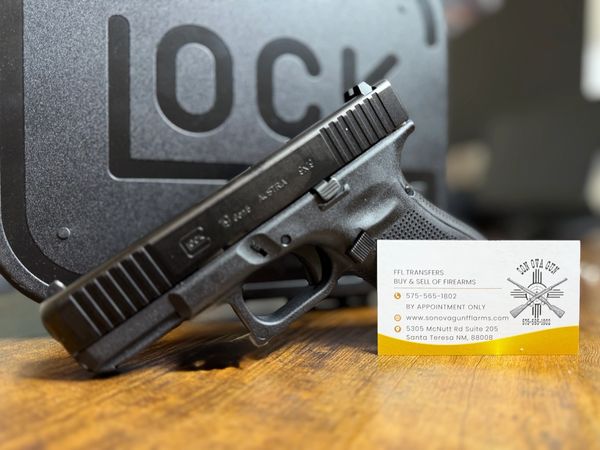 A Glock handgun leaning against its case with a firearm business card nearby.