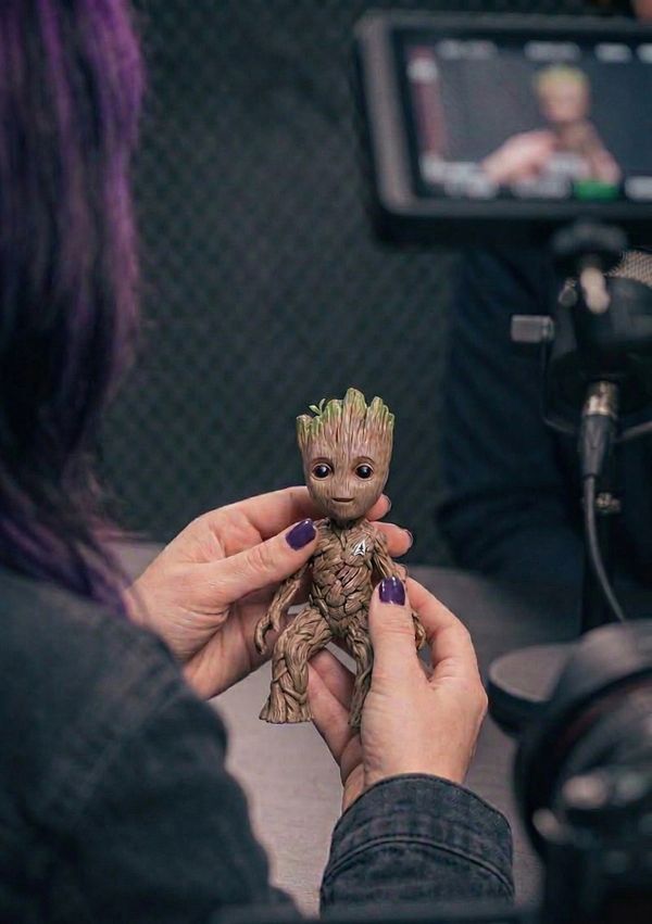 Person holding a detailed Baby Groot figurine with purple-painted nails.