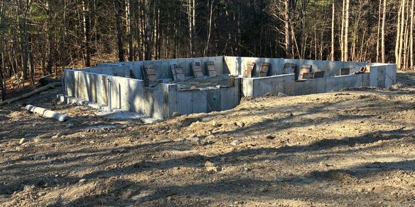 Concrete foundation laid for a new building in a wooded area.