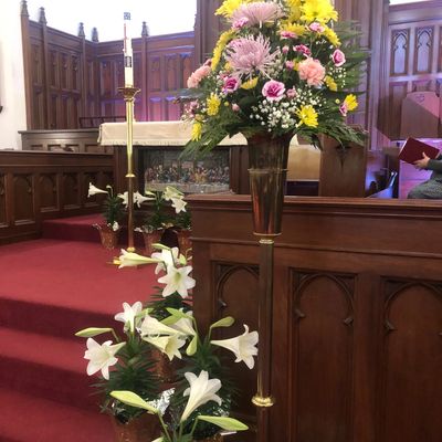 Floral arrangements inside a church near the altar and steps.