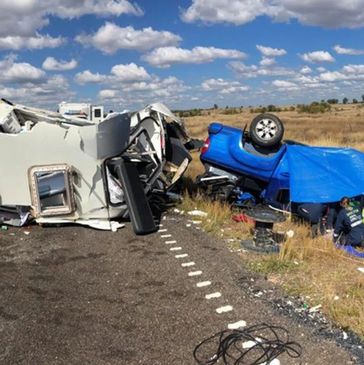 Overturned vehicles after a crash on a rural road under a partly cloudy sky.
