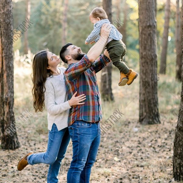 Happy family playing with their child in a forest.