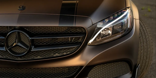Close-up of Mercedes car front with sleek matte finish and headlight.