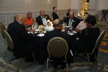Group of people dressed formally at a dinner table.