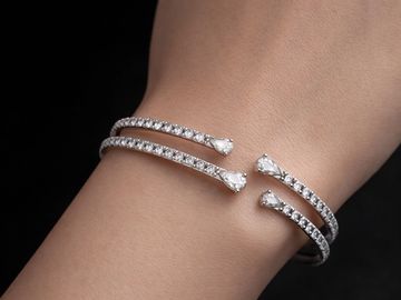 Elegant double-band diamond bracelet with pear-shaped ends on wrist.