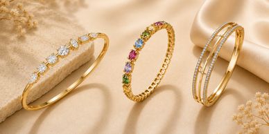 Three elegant gold rings with diamonds and multicolored gemstones on a beige surface.