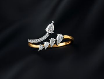 Elegant gold ring with pear-shaped diamonds on black background.