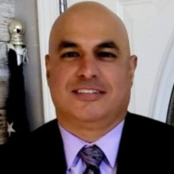 A smiling man in a suit and tie posing indoors.