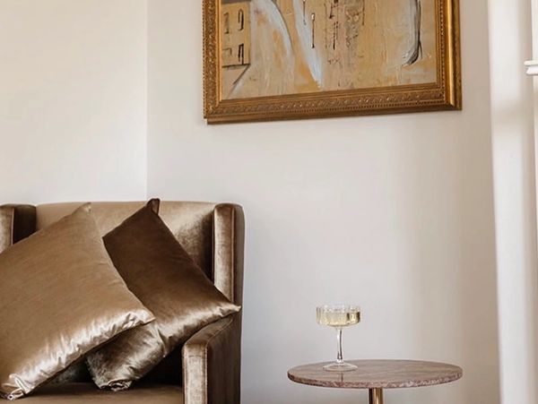 Elegant armchair with plush pillows beside a small round table and abstract wall art.