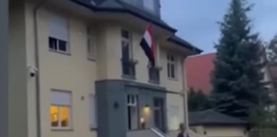 A multi-story house with a flag hanging outside on a cloudy day.