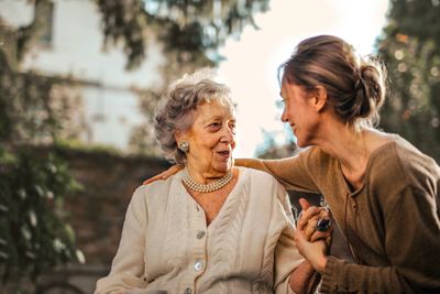 A woman helping to care for an elderly senior in the comforts of her own backyard