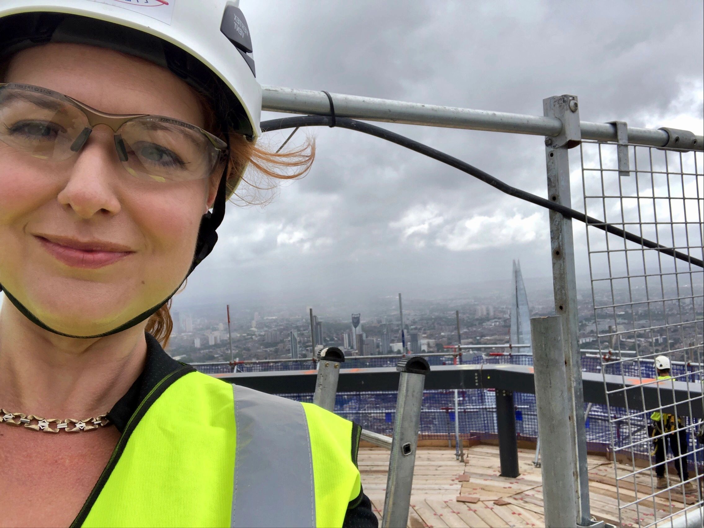 Woman in PPE on top of a skyscraper with London skyline in the background.