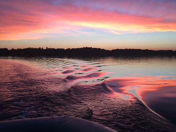 Sunset reflecting beautifully on calm lake water with ripples.
