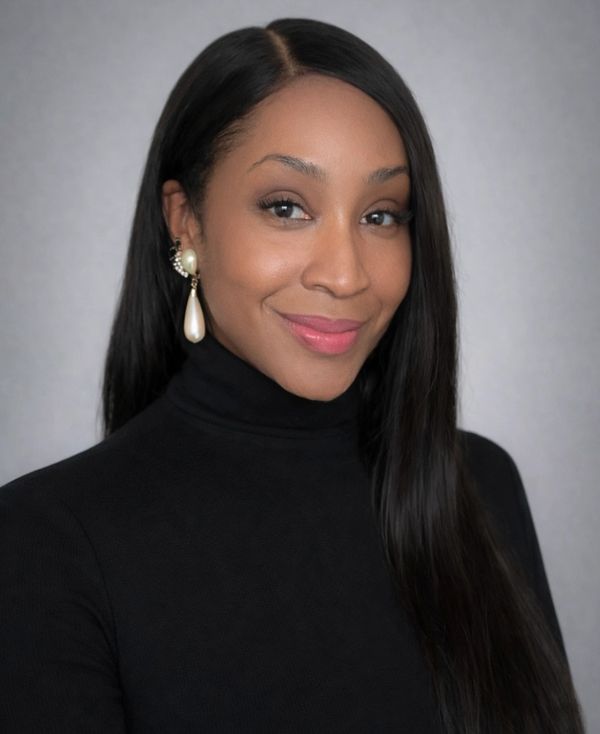 Woman with long black hair wearing pearl earrings and a black turtleneck.
