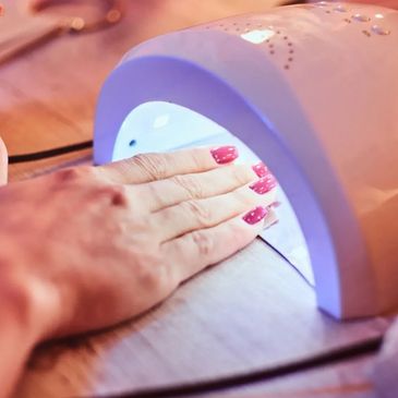 Hand drying freshly painted nails under a UV nail lamp.