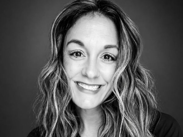 Black and white portrait of a smiling woman with wavy hair.