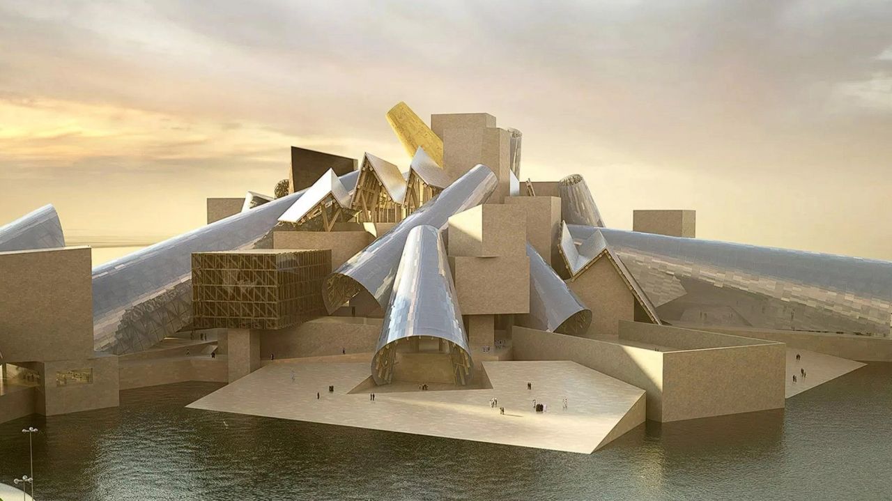 A modern architectural structure with abstract, angular shapes and a mix of glass and stone materials, situated by a body of water under a cloudy sky.