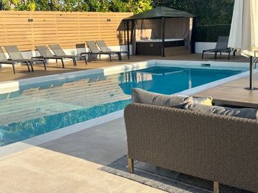 Modern backyard pool area with lounge chairs and a shaded cabana.