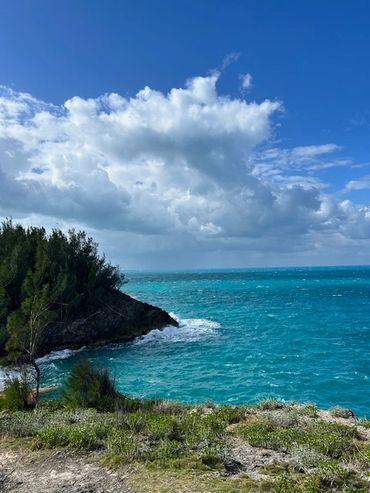 Scenic coastal view with turquoise sea and cloudy sky.