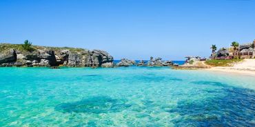 Crystal-clear turquoise water meets rocky coastline under a bright blue sky.