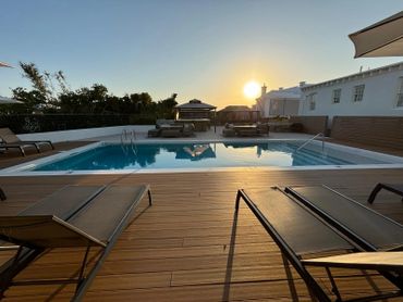 Sunset over a serene poolside with lounge chairs and modern seating.