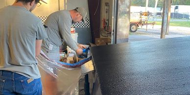 Two men working on a project inside a garage or workshop.